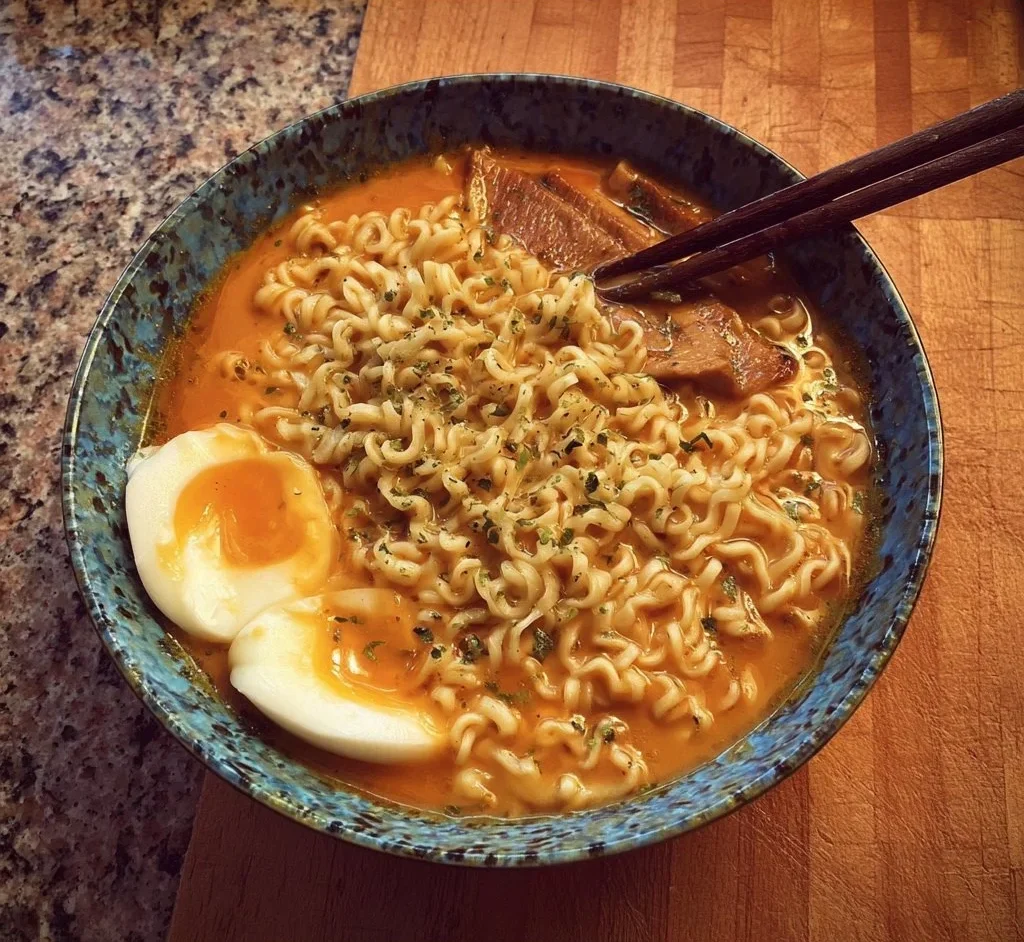 A bowl of delicious ramen soup garnished with dumplings and green onions.