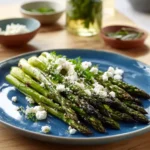 Grilled asparagus garnished with lemon and herbs on a plate