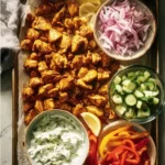 Plate of sheet pan chicken pitas with fresh vegetables and sauce.